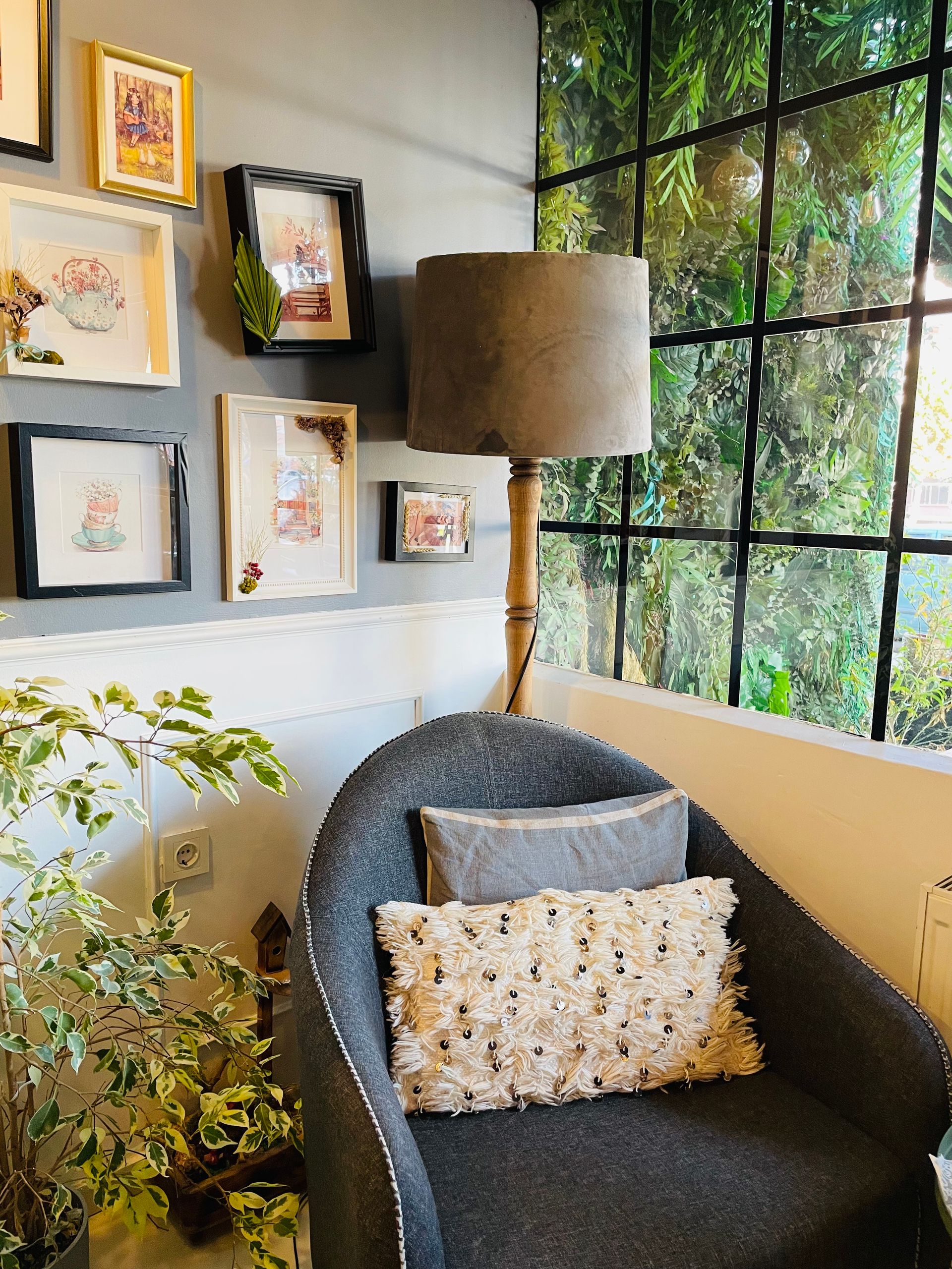 Una acogedora zona de estar que cuenta con un sillón, una lámpara de pie y una obra de arte enmarcada junto a una ventana.